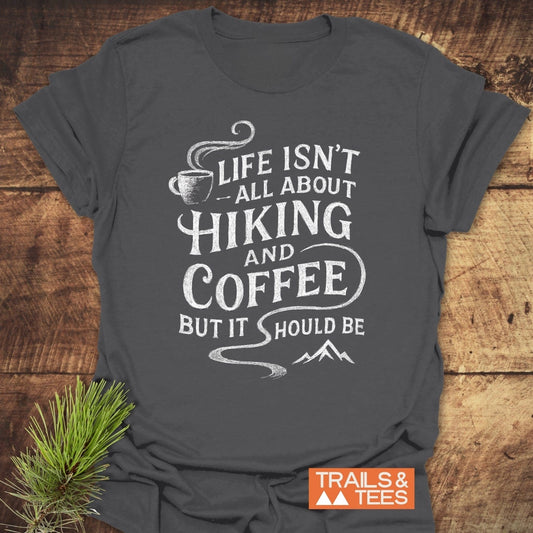 Charcoal-gray Hiking and Coffee T-Shirt featuring a white coffee cup and mountain design, emphasizing comfort and adventure. Includes Trails & Tees logo.