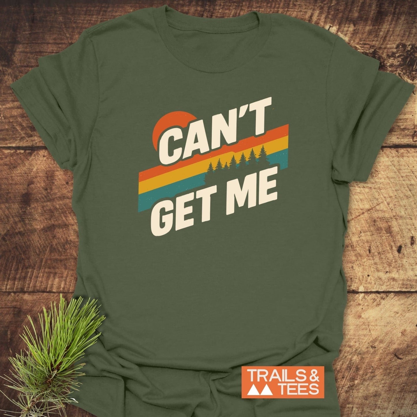 Can't Get Me Hiking T-Shirt with retro sunset graphic and text, laid on wood. Features soft ring-spun cotton, taped shoulders, and durable print.