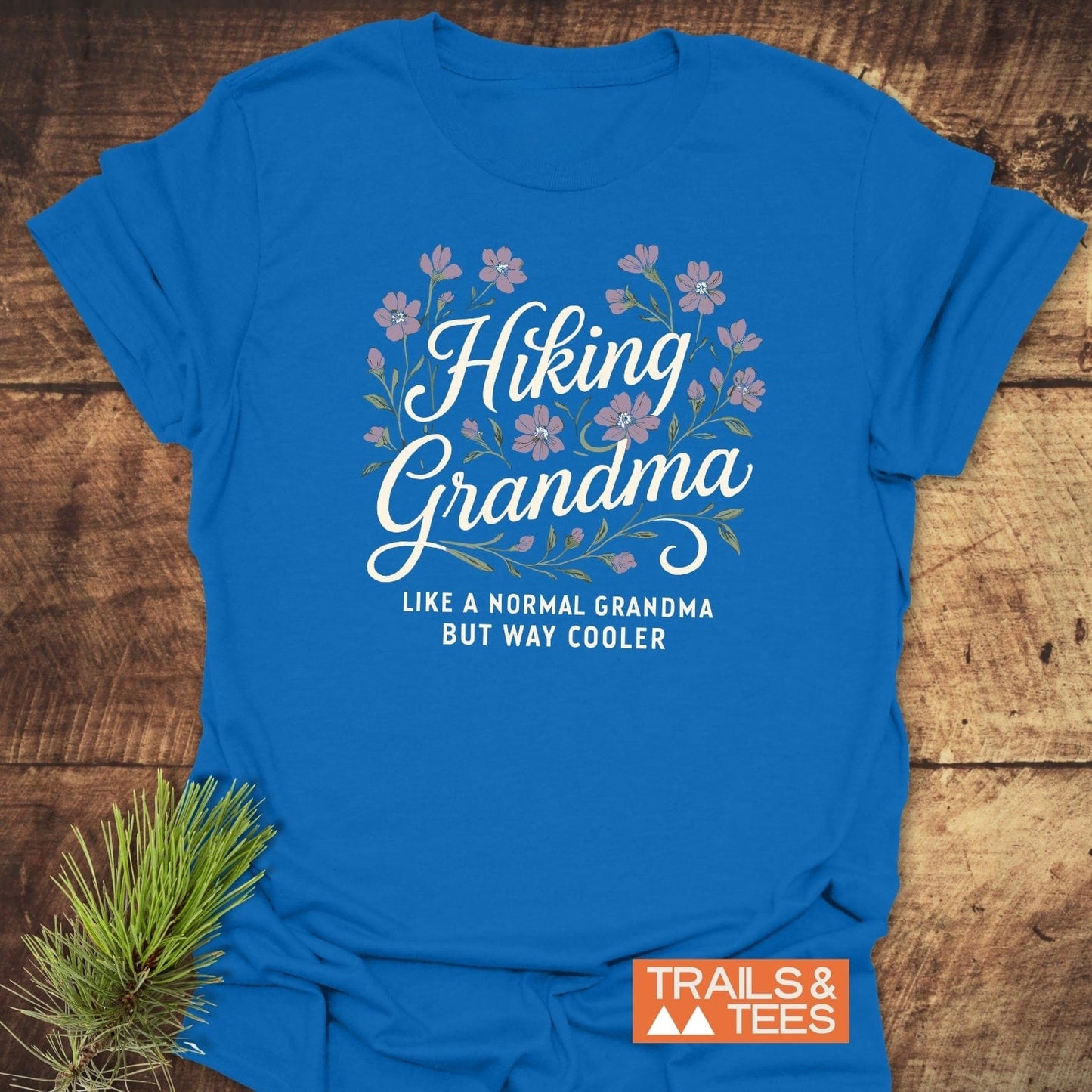 Hiking Grandma Floral T-Shirt with slogan and Trails & Tees logo, styled with pine needles; crafted from soft, lightweight cotton for outdoor adventures.
