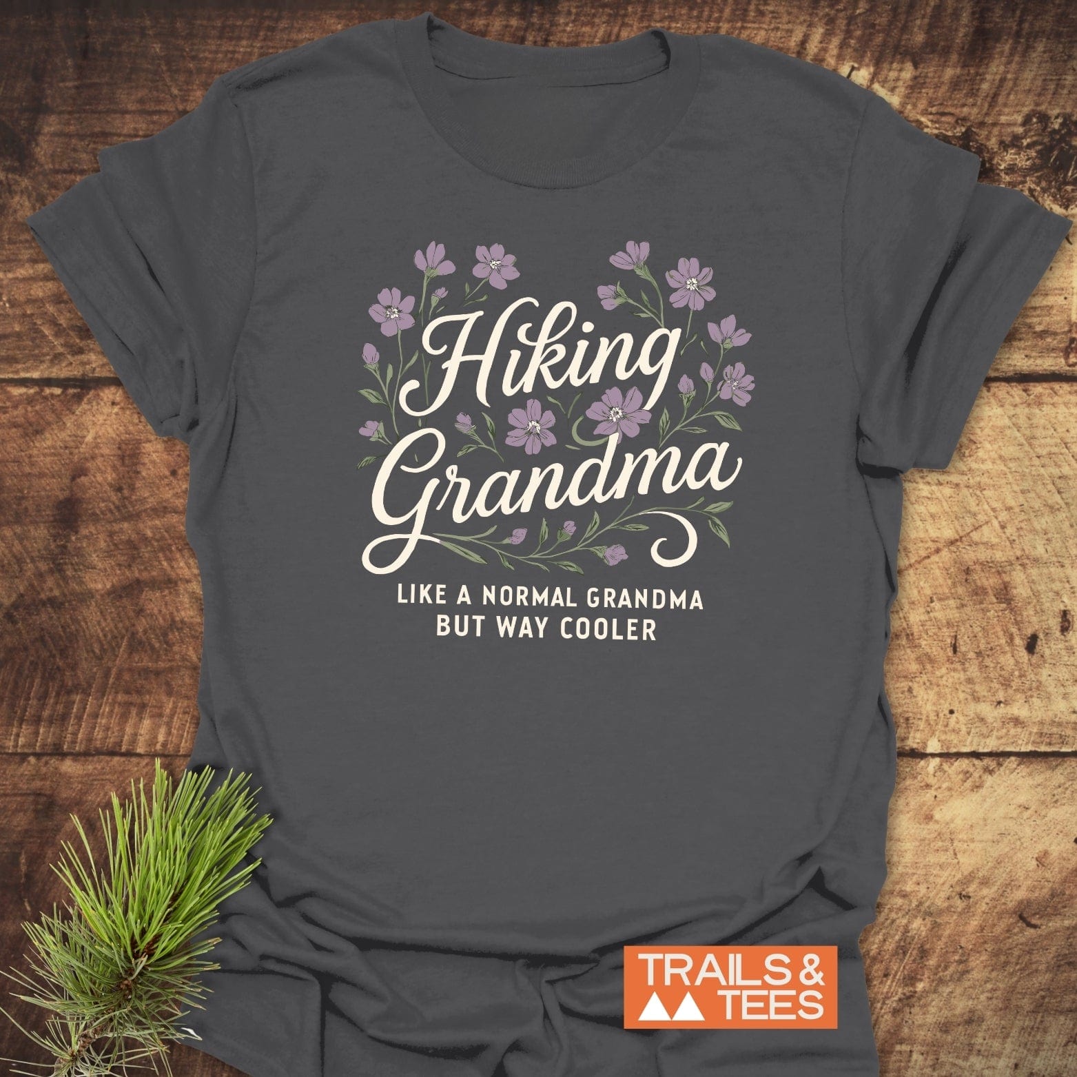 Charcoal-gray Hiking Grandma T-shirt with floral design, crafted from soft cotton, featuring durable prints. Ideal for outdoor enthusiasts, promoting comfort and adventure.