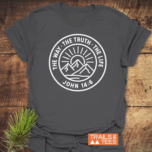 The Way, The Truth, The Life T-Shirt with mountain graphic, crafted from soft cotton for comfort and durability, laid on wood with pine sprig.