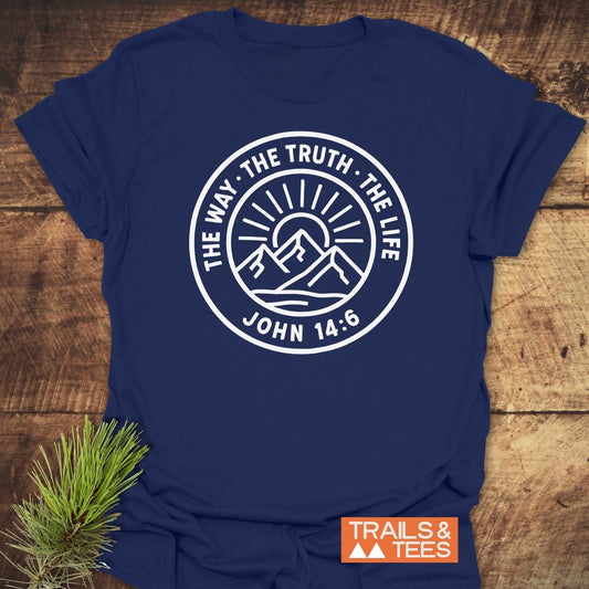 Navy-blue T-shirt with a badge graphic The Way, The Truth, The Life over mountains, branded TRAILS & TEES, highlighting outdoor adventure and comfort.
