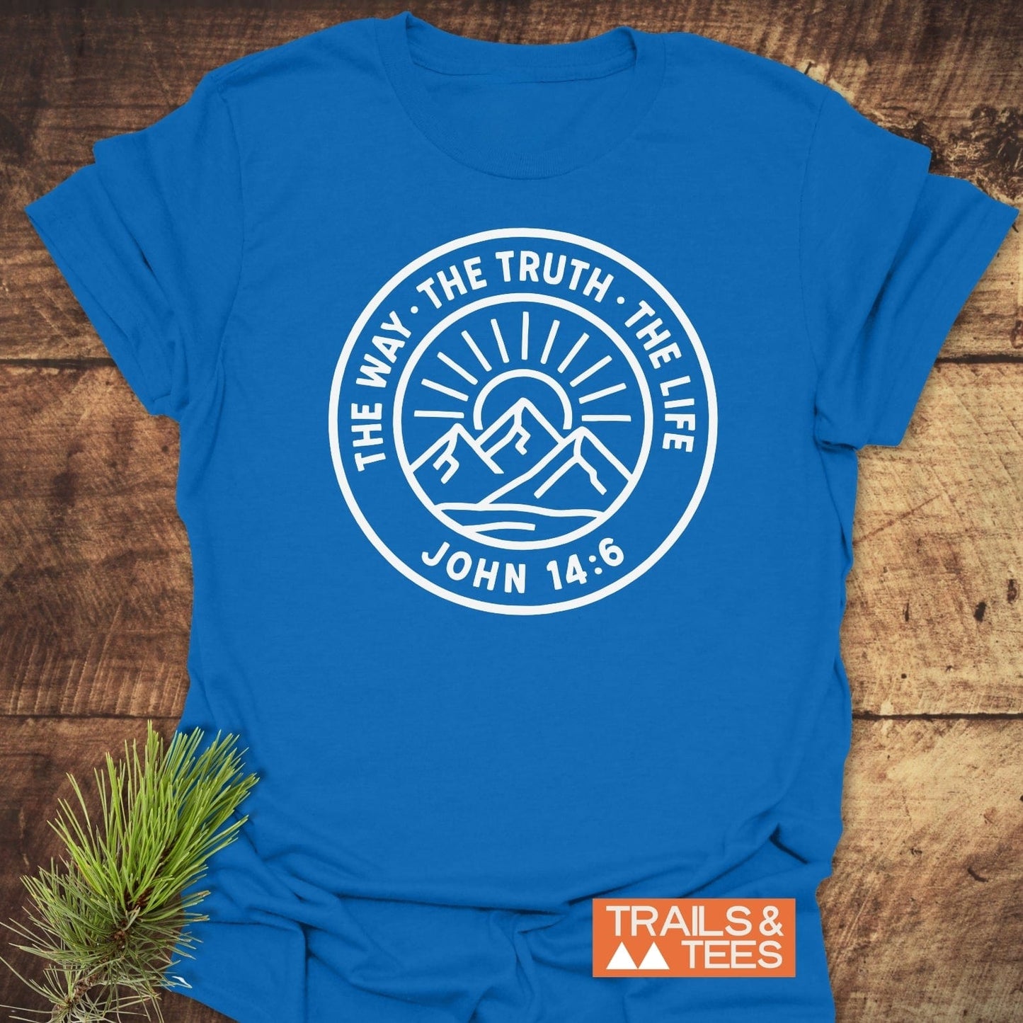 The Way, The Truth, The Life T-Shirt with mountain graphic and scripture, laid on wood. Features soft cotton, durable print, and eco-conscious design by Trails & Tees.