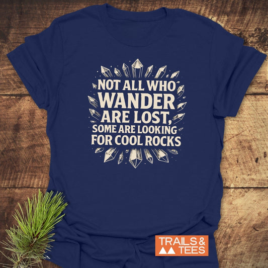 Navy-blue 764 Not All... Rock Lover T-Shirt with white lettering and crystal illustrations, laid on wood with pine sprig, featuring Trails & Tees logo.