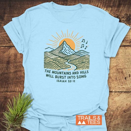 Mountains And Hills T-Shirt with a sunrise mountain illustration and Isaiah 55:12 verse, laid flat. Features durable print, soft cotton, and taped shoulders for comfort.