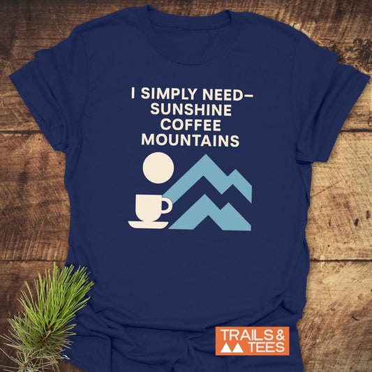 Geometric Mountain Love T-Shirt with “I SIMPLY NEED – SUNSHINE COFFEE MOUNTAINS” text and icons, showcasing outdoor spirit and comfort. Ideal for adventure lovers.