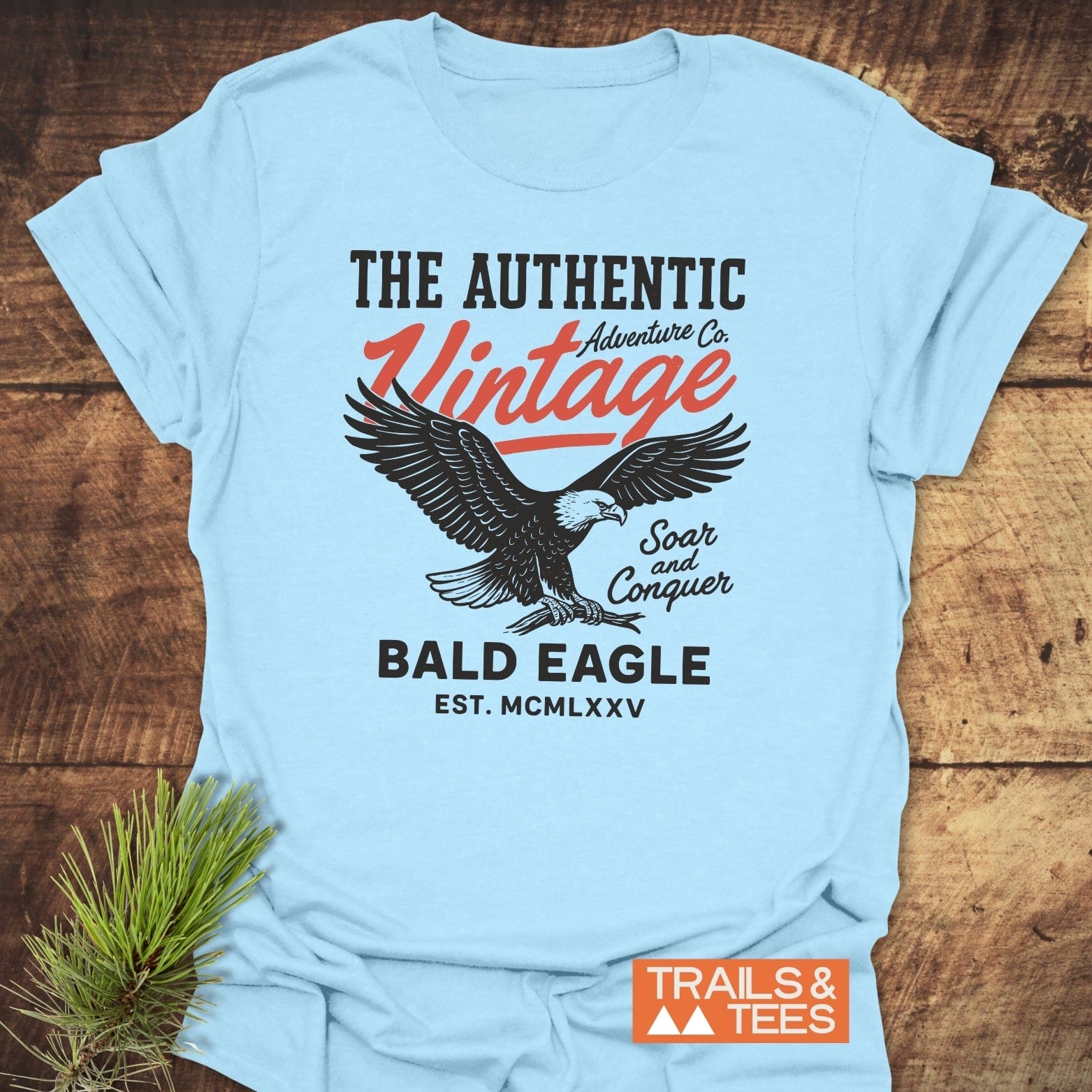 Vintage Bald Eagle T-Shirt featuring a soaring eagle graphic with THE AUTHENTIC Adventure Co. and Soar and Conquer, styled with pine sprig, embodying timeless outdoor adventure.