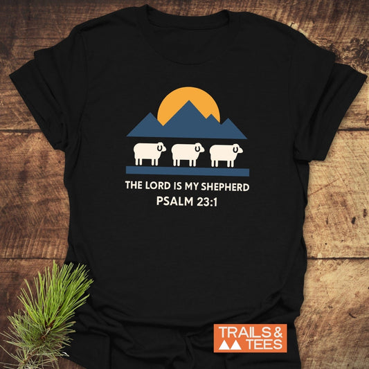 The Lord Is My Shepherd T-Shirt featuring a sun, mountains, and sheep design. Made of soft cotton, durable prints, pre-shrunk, and taped shoulders for comfort.