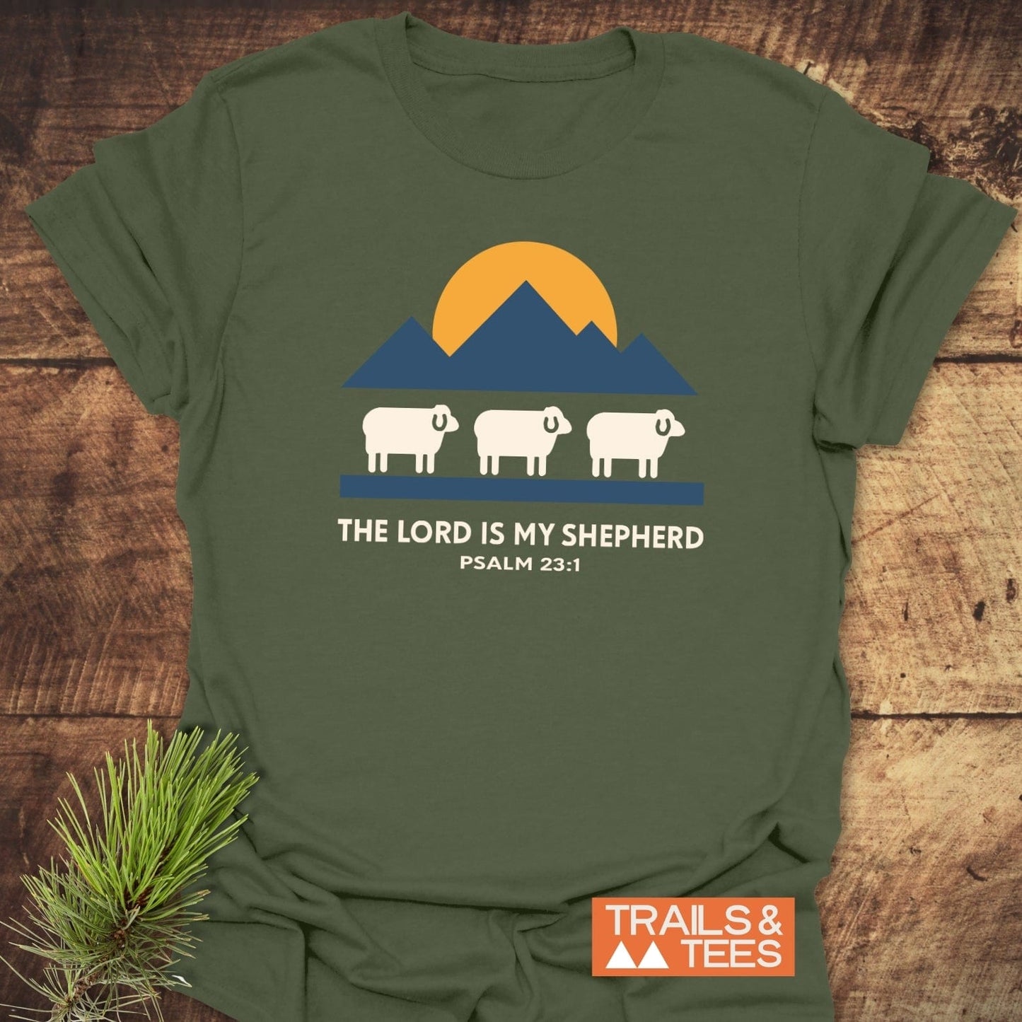 The Lord Is My Shepherd T-Shirt features sheep and mountains graphic, Psalm 23:1 text, crafted from soft cotton for everyday outdoor adventures.
