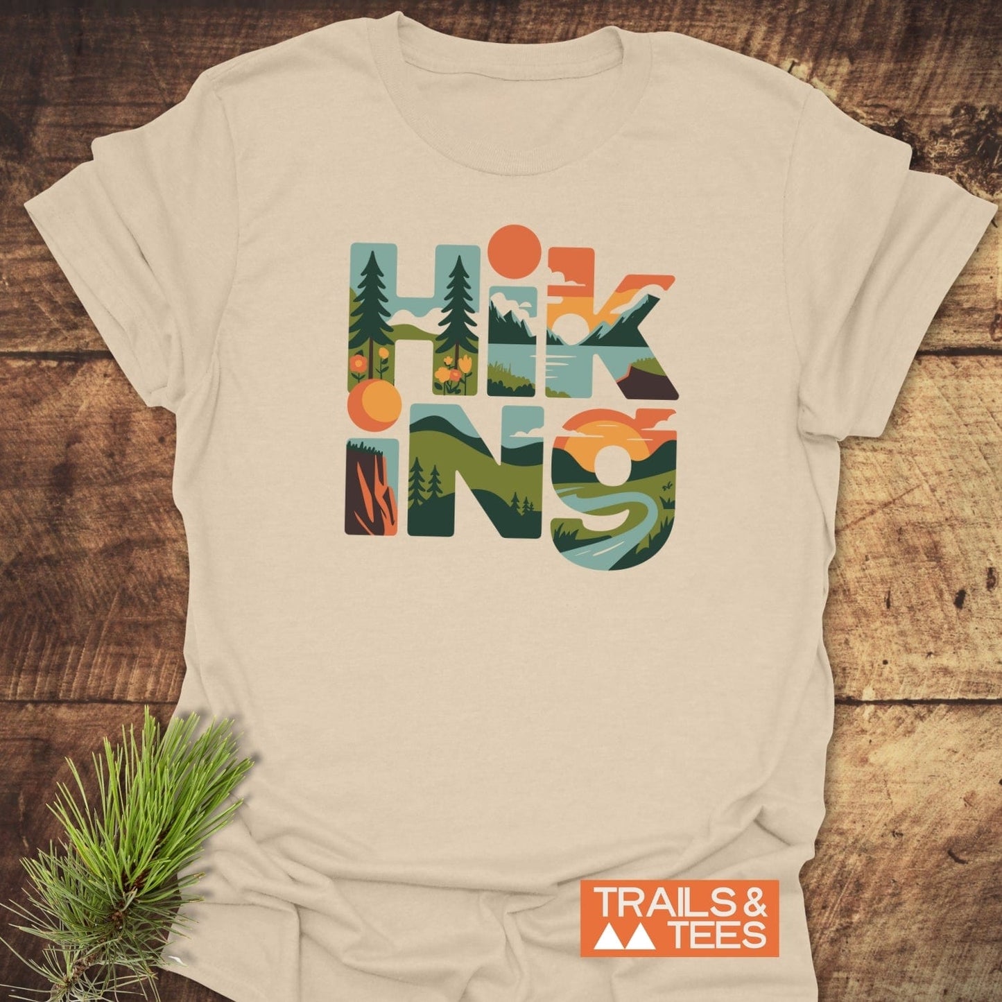 Hiking Typographic T-Shirt with outdoor scene-filled letters, crafted from soft ring-spun cotton. Features durable prints and taped shoulders for lasting comfort.