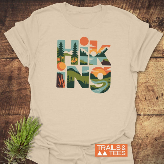 Hiking Typographic T-Shirt with outdoor scene-filled letters, crafted from soft ring-spun cotton. Features durable prints and taped shoulders for lasting comfort.