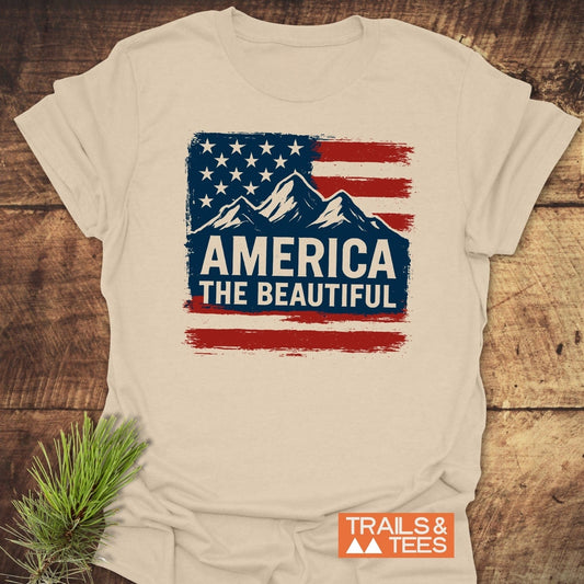 America The Beautiful T-Shirt featuring a distressed flag and mountain design, showcasing outdoor spirit. Made from soft ring-spun cotton for comfort and durability.