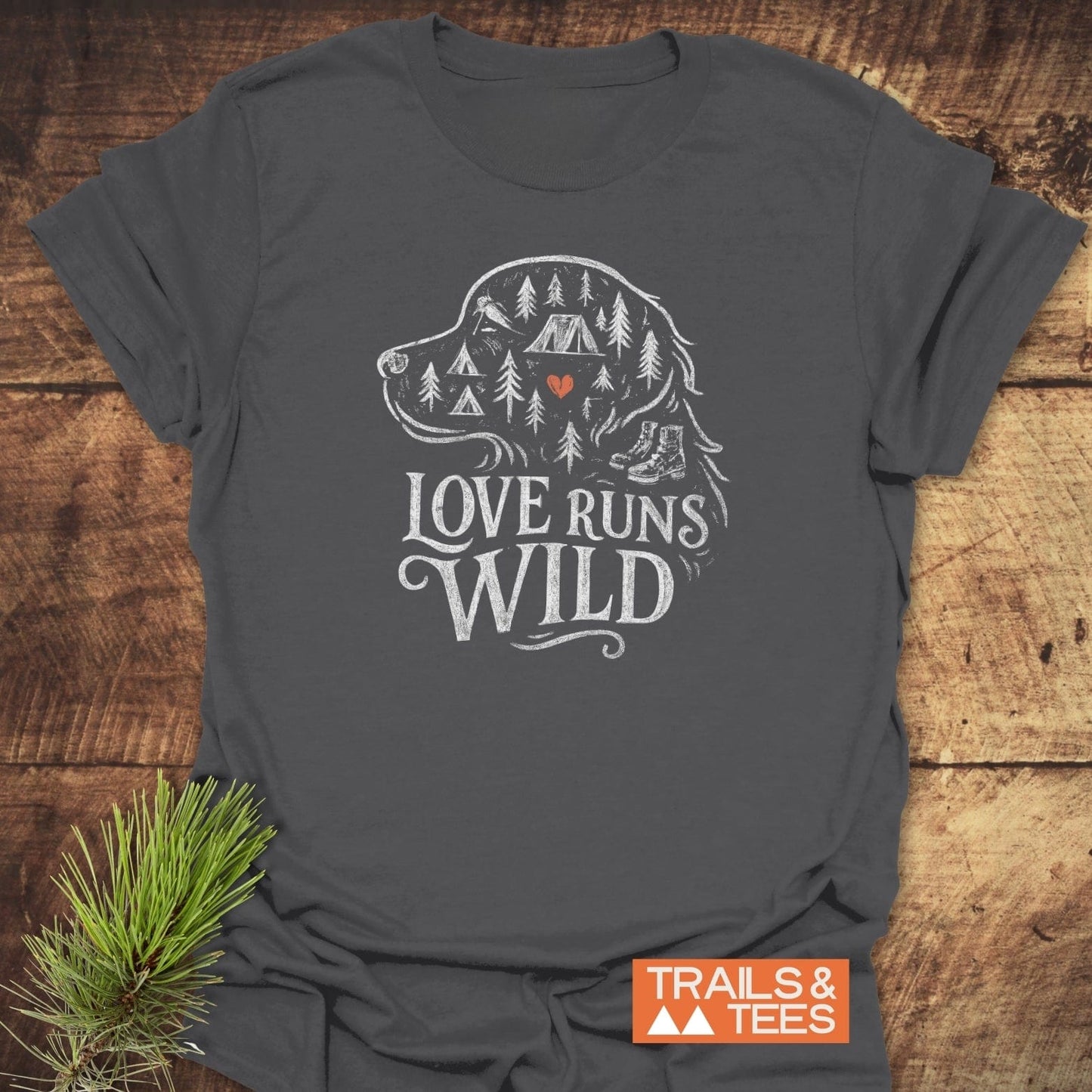 Love Runs Wild T-Shirt featuring a dog head outline with pine trees, tent, and boots design, slogan “LOVE RUNS WILD,” and Trails & Tees logo.