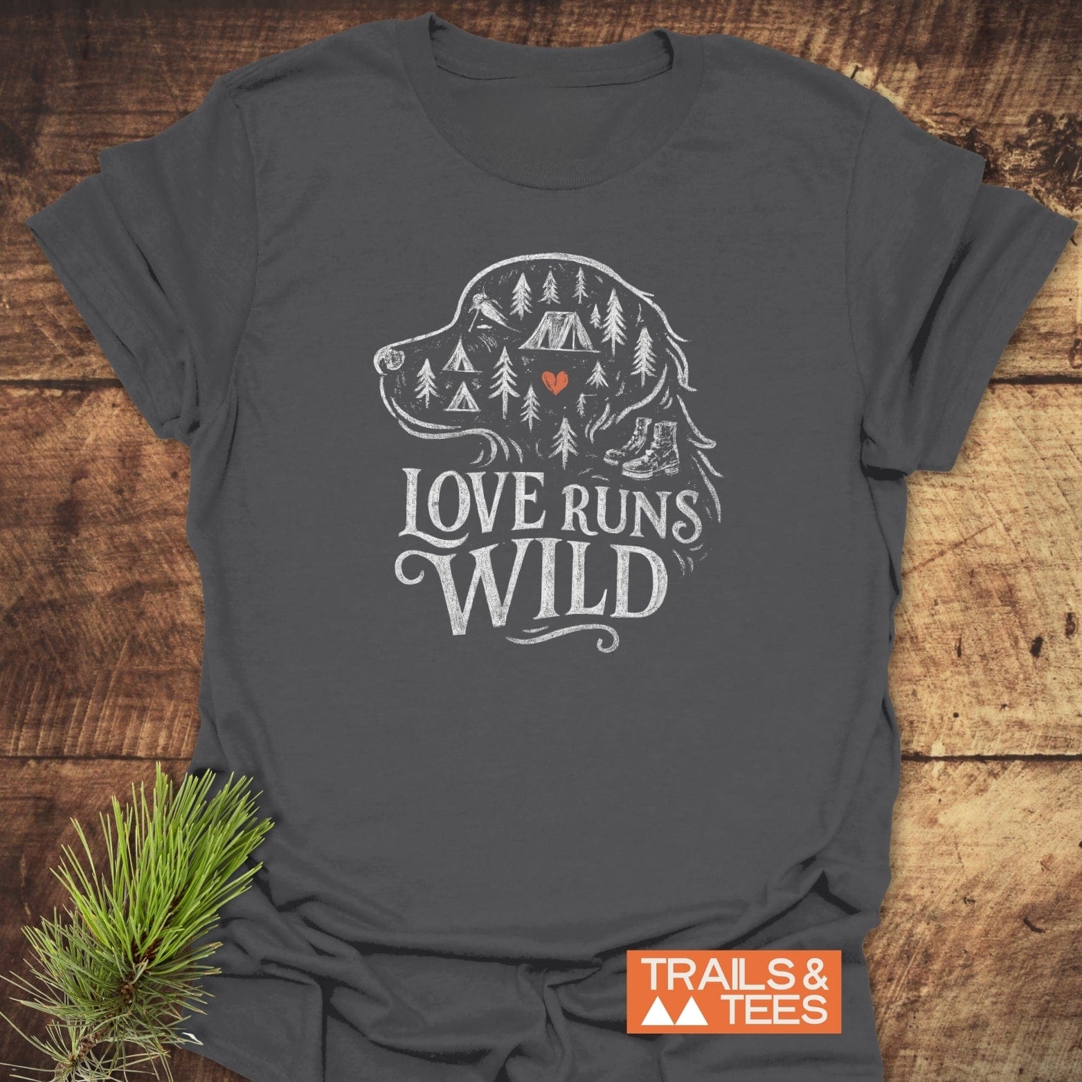 Love Runs Wild T-Shirt featuring a dog head outline with pine trees, tent, and boots design, slogan “LOVE RUNS WILD,” and Trails & Tees logo.