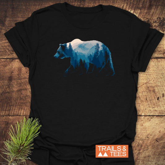 Grizzly Silhouette T-Shirt featuring a bear with mountain scene graphic, laid on wood. Includes TRAILS & TEES badge. Made from soft, lightweight cotton.
