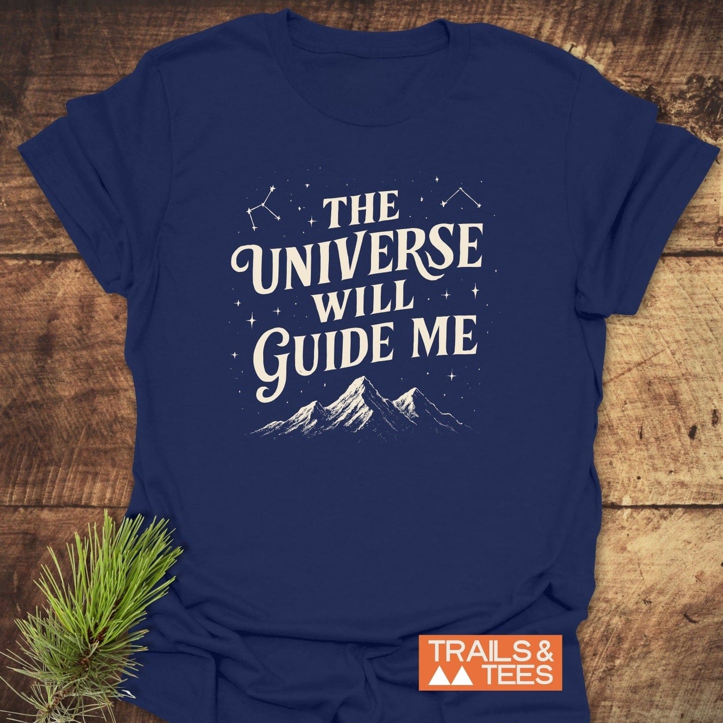 Navy-blue The Universe Guides Me T-shirt with constellations, mountain silhouette, and slogan. Soft, durable cotton with rustic pine accent.