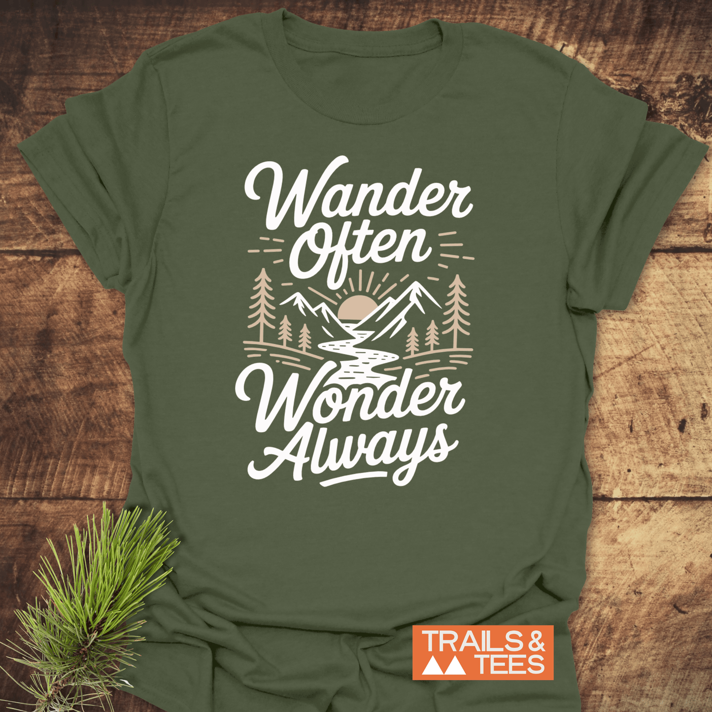 Wander Often T-Shirt featuring an outdoor scene with a mountain, river, trees, and sun. Soft cotton, durable print, and pre-shrunk for comfort and sustainability.