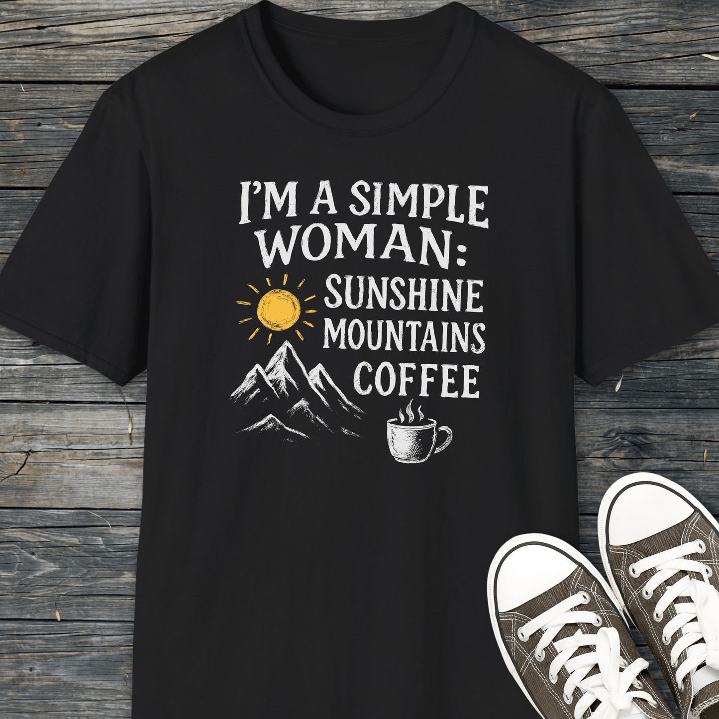 Simple Woman Sunshine T-Shirt featuring a sun, mountains, and coffee design, laid on wood with canvas sneakers. Perfect for outdoor enthusiasts seeking comfort and style.