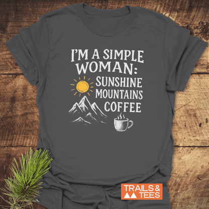 Simple Woman Sunshine T-Shirt on wood surface, featuring sun, mountain, and coffee mug designs. Crafted from ring-spun cotton with durable print and taped shoulders.