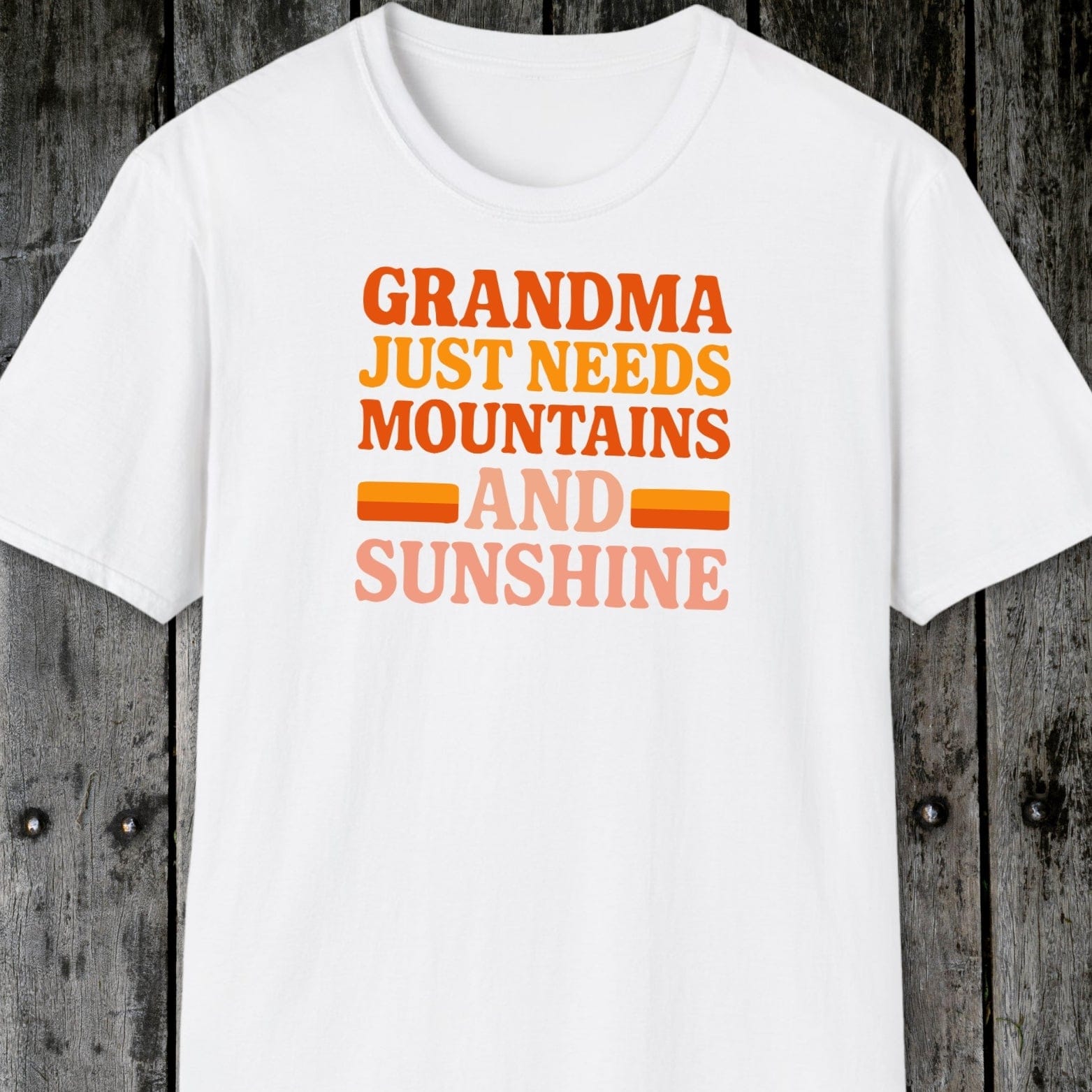 Retro 80s Grandma Mountains T-Shirt with warm-toned slogan, laid flat. Crafted from soft cotton, featuring durable prints and taped shoulders for lasting comfort.