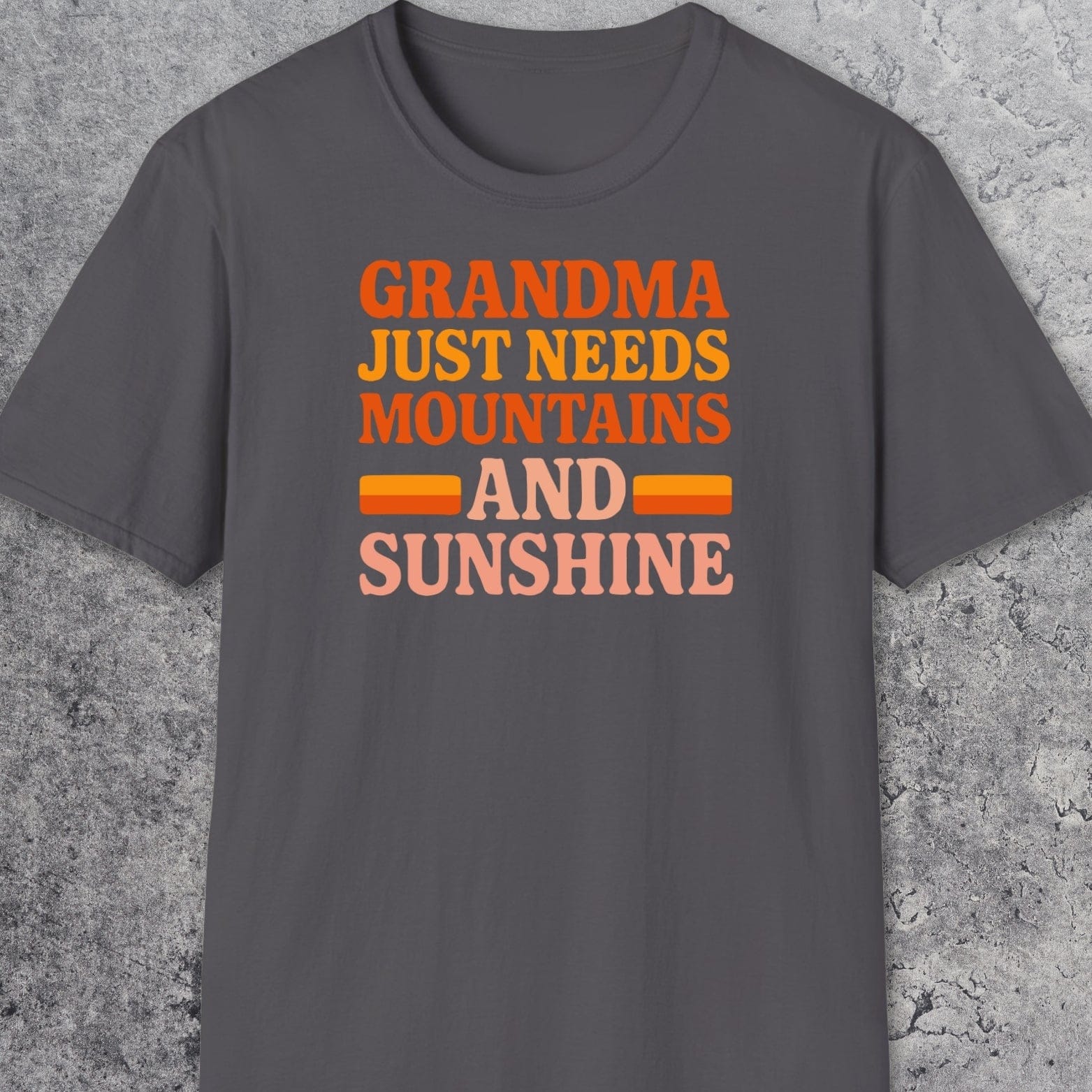 Retro 80s Grandma Mountains T-Shirt laid flat, features warm-toned text celebrating nature. Made from soft, ring-spun cotton for comfort and durability.