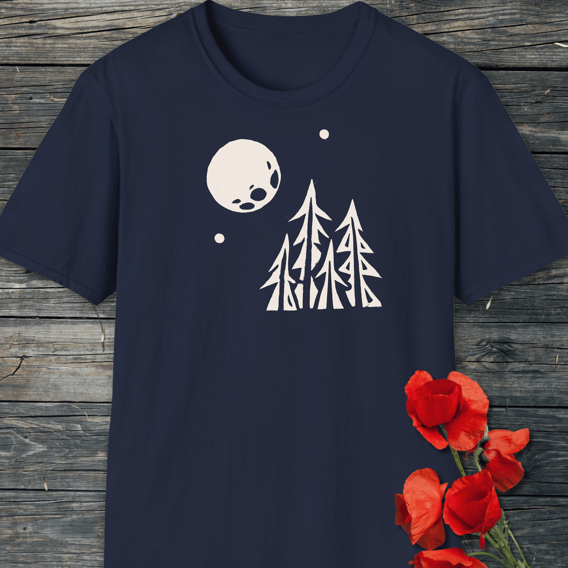 Pine Trees and Full Moon T-Shirt on wood, featuring white tree and moon graphic; soft, lightweight cotton, ideal for outdoor enthusiasts.