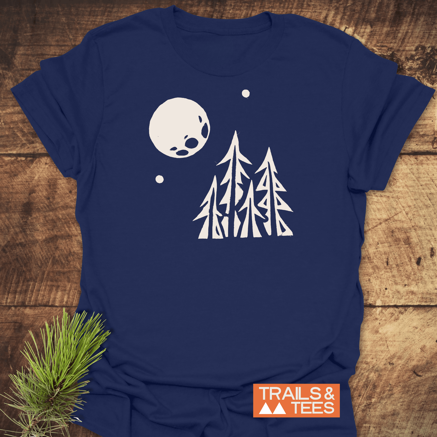 Navy-blue Pine Trees and Full Moon T-Shirt, featuring a serene night-time forest scene. Soft, ring-spun cotton ensures comfort and durability for outdoor enthusiasts.