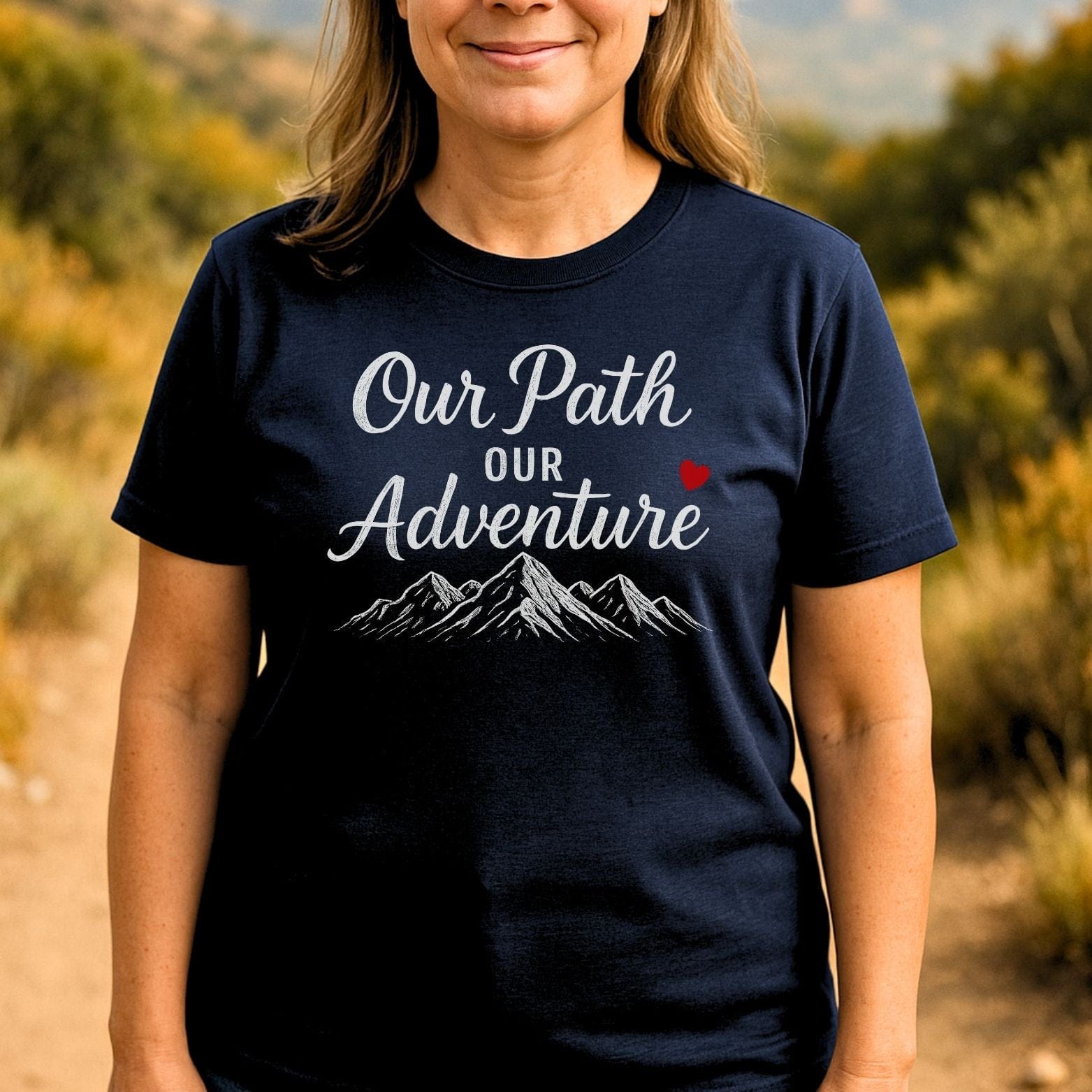 Person wearing Our Path Couple T-Shirt with mountain graphic and red heart, standing on a nature trail, highlighting outdoor adventure spirit and comfort.