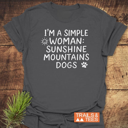 Charcoal T-shirt with I'M A SIMPLE WOMAN: SUNSHINE MOUNTAINS DOGS in white text, featuring sun and paw-print icons. Logo: TRAILS & TEES.