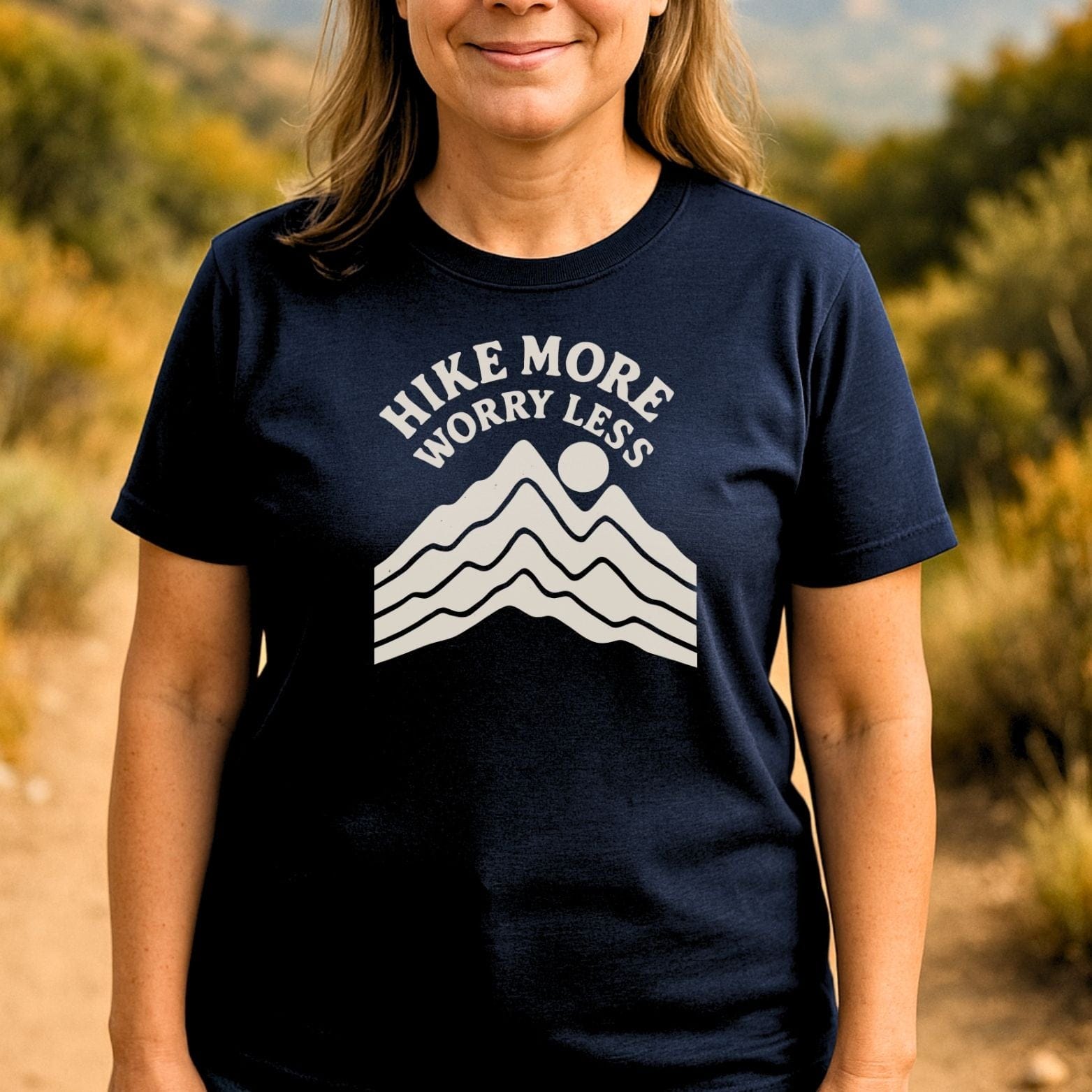 Person wearing a navy T-shirt with mountain graphic and HIKE MORE WORRY LESS slogan, designed for comfort and adventure, crafted from lightweight ring-spun cotton.