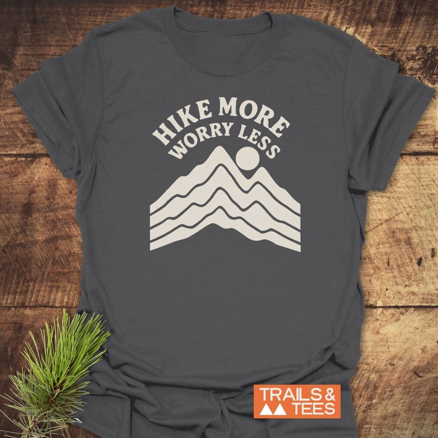 Dark-gray Hike More Worry Less T-shirt with mountain graphic, laid flat. Made from soft ring-spun cotton, features durable print, designed for outdoor enthusiasts.