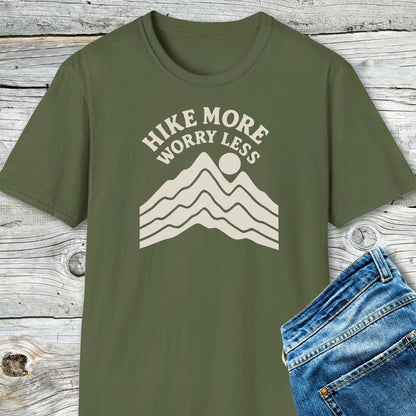 Hike More Worry Less T-Shirt featuring a cream mountain and sun graphic, highlighting its soft ring-spun cotton and durable print on a wooden backdrop.