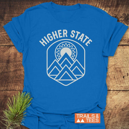 Higher State Mountain Mandala T-Shirt features a white mountain and sun graphic on a royal-blue tee, showcasing outdoor-inspired design and comfort.