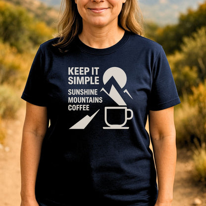Person wearing the Keep It Simple Mountain T-Shirt, featuring a sun, mountain, and coffee mug graphic, embodying outdoor adventure themes.