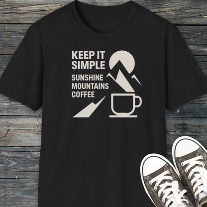 Keep It Simple Mountain T-Shirt with “KEEP IT SIMPLE” graphic, sun-mountain-coffee icon, and classic low-top dark canvas sneakers on a wooden surface.