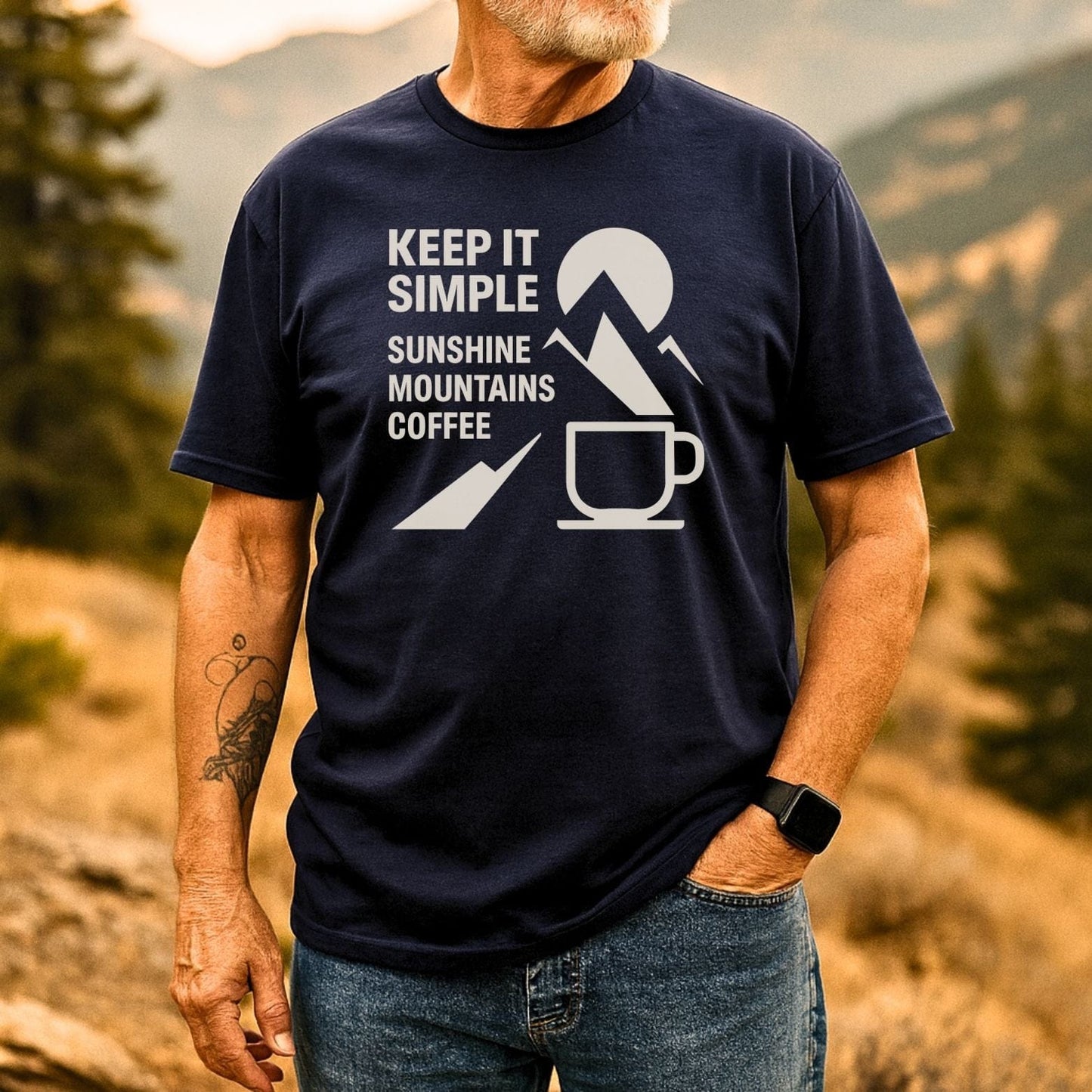 Man outdoors in Keep It Simple Mountain T-Shirt, featuring sun, peaks, coffee print. Wears jeans, smartwatch, showcasing lightweight, durable outdoor apparel.
