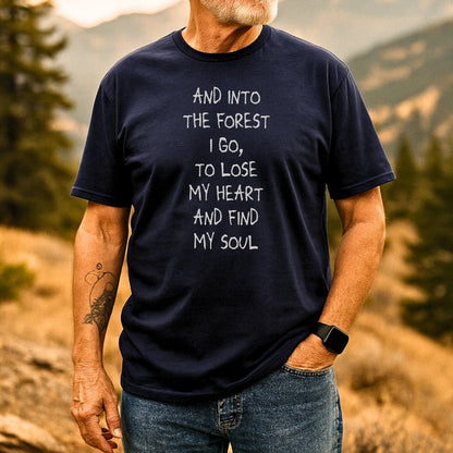 Man in navy And Into The Forest I Go T-Shirt, standing in nature, showcasing trail-tested comfort and outdoor-themed design, ideal for adventure seekers.
