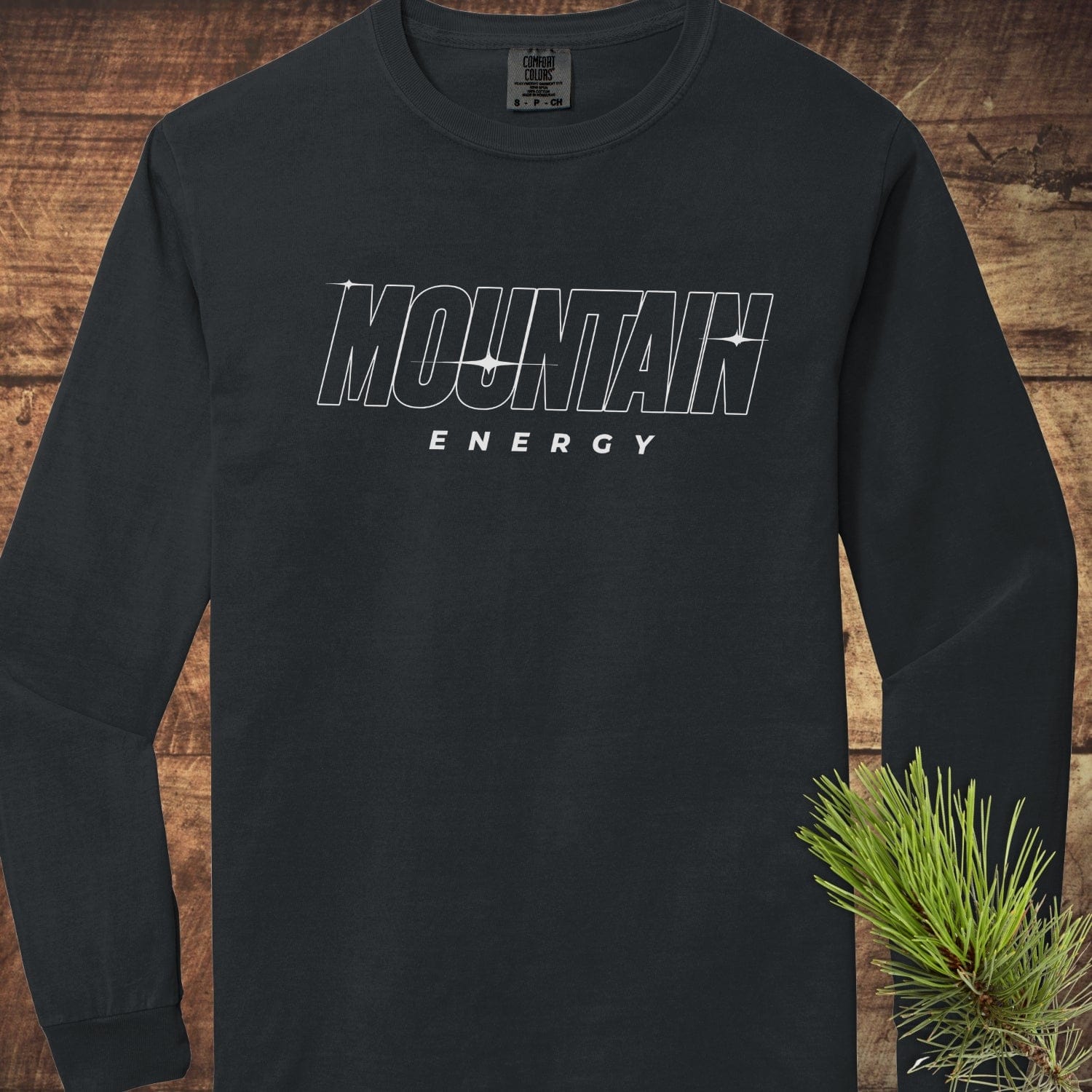 Mountain Energy Comfort Colors Longsleeve Tee, black with bold lettering, laid flat, showcasing soft, 100% ring-spun cotton fabric and relaxed fit.