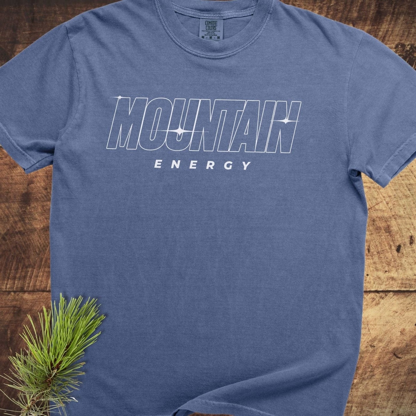 Mountain Energy Comfort Colors 1717 Tee displayed flat with MOUNTAIN ENERGY graphic, highlighting its rustic style and soft, durable garment-dyed cotton fabric.