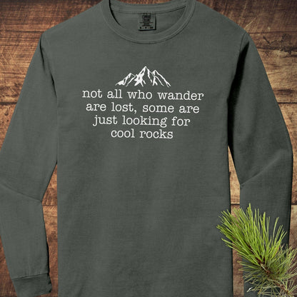 Looking For Cool Rocks Comfort Colors Long-Sleeve Tee with mountain design, laid on wood surface, featuring 100% ring-spun cotton for softness and style.