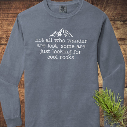 Looking For Cool Rocks Comfort Colors Long-Sleeve Tee, slate-blue, with mountain graphic and quote, laid on wood surface, next to pine sprig. 100% ring-spun cotton.