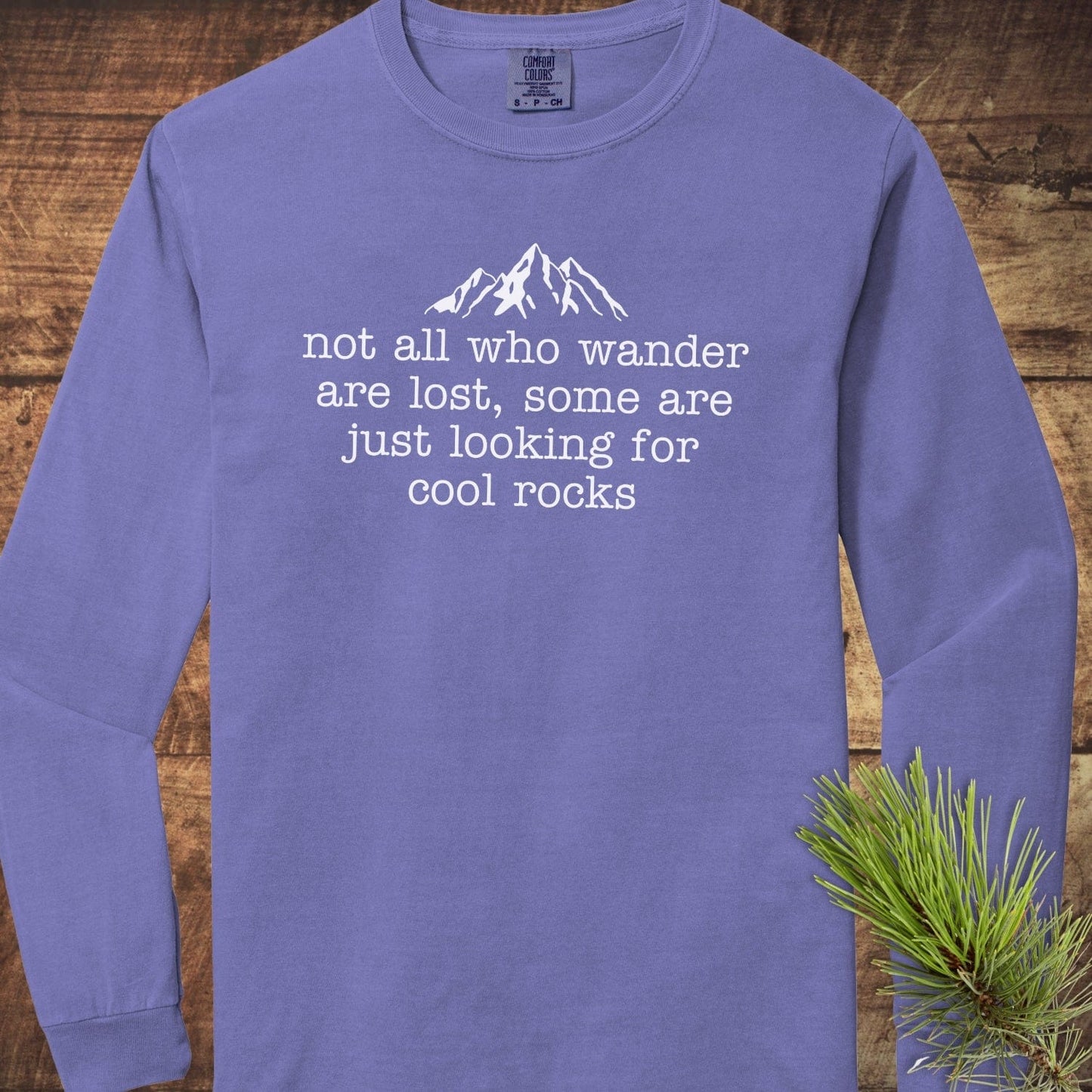 Looking For Cool Rocks Comfort Colors Long-Sleeve Tee with mountain print, laid on wood, features 100% ring-spun cotton for softness and relaxed fit.