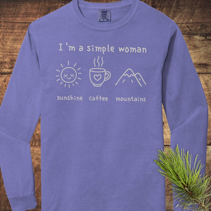 I'm A Simple Woman Comfort Colors Long-Sleeve Tee on wooden surface, featuring a white graphic with sun, coffee, mountains icons and text, 'sunshine, coffee, mountains.'