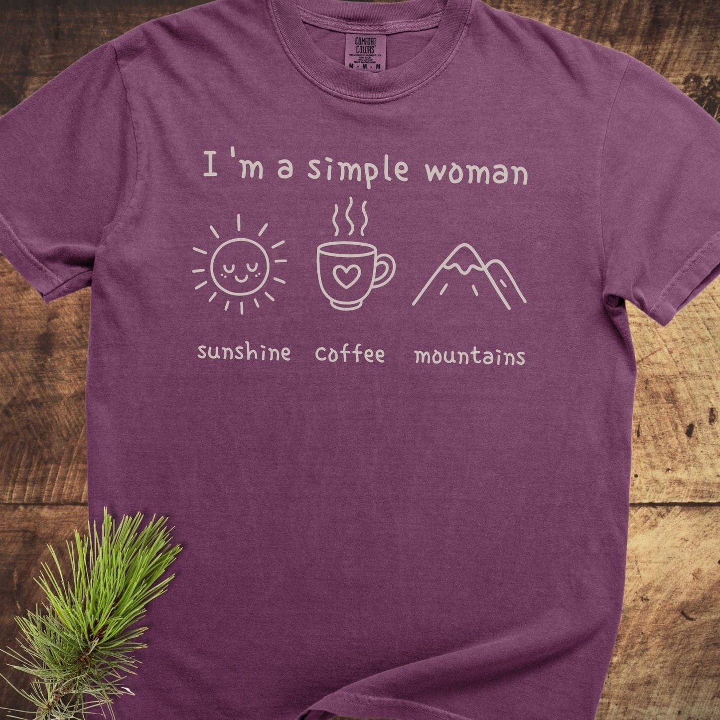 I'm A Simple Woman Comfort Colors 1717 Tee, purple, laid flat, features white text and icons of sun, coffee, mountains, showcasing its relaxed, durable design.