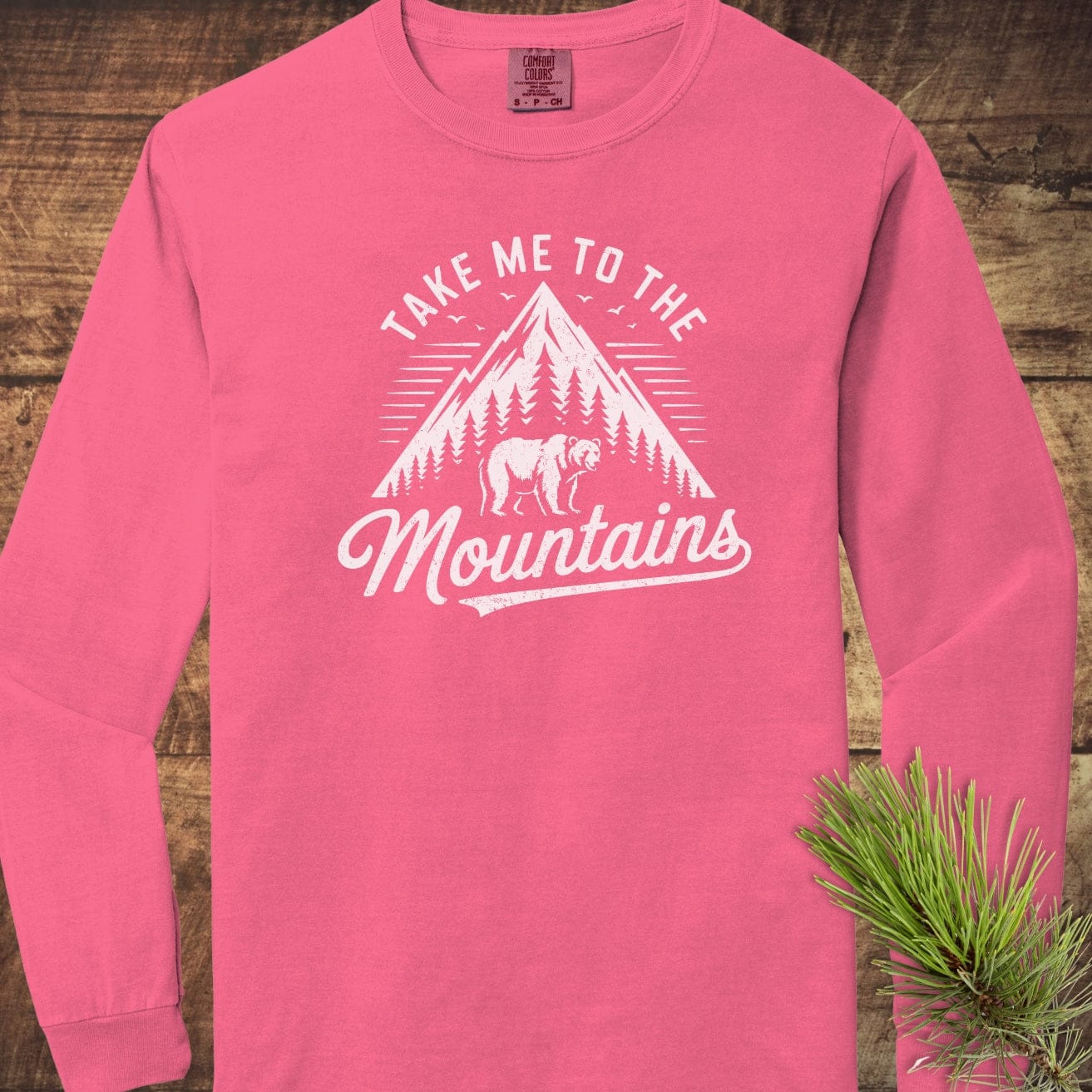 Copy of Mountain Energy Comfort Colors Long-Sleeve Tee featuring a vintage mountain graphic and bear, laid flat with pine needles on the side.