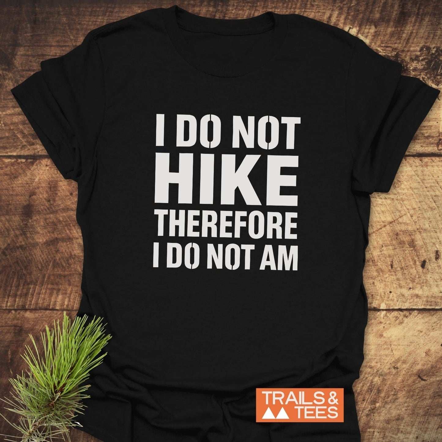 Black T-shirt with “I DO NOT HIKE THEREFORE I DO NOT AM” in white text. Corner logo: “TRAILS & TEES.” Designed for comfort and outdoor enthusiasts.