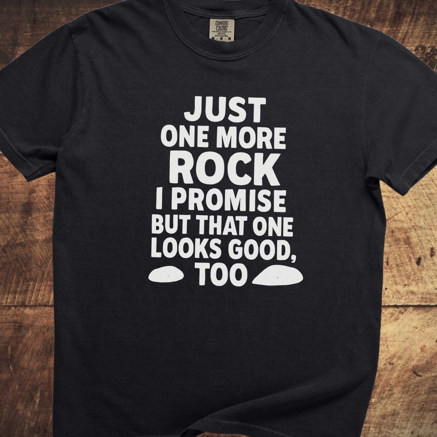 Just One More Rock Funny Comfort Colors 1717 Tee with humorous text and rock graphics, laid on wood surface; black, medium, 100% ring-spun cotton, relaxed fit.