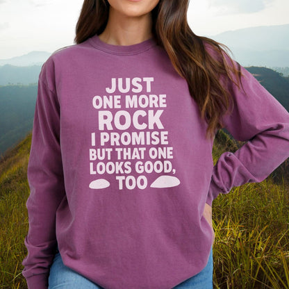 Person outdoors in a grassy area wearing the Just One More Rock Comfort Colors Long-Sleeve Tee with playful white slogan and rock icons on purple fabric.