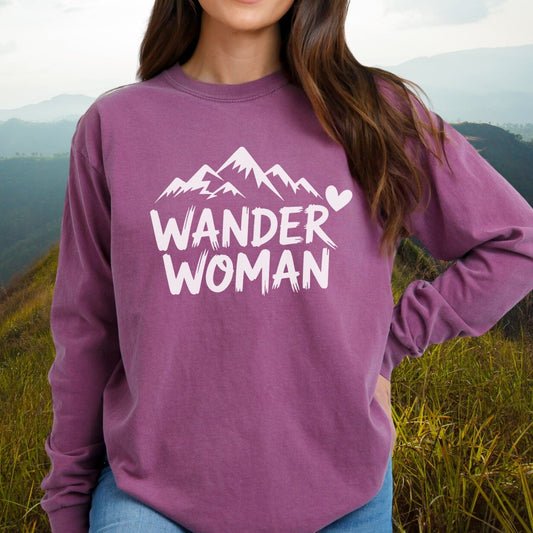 Person in grassy landscape wearing the Wander Woman Comfort Colors Long-Sleeve Tee with mountain and heart design, highlighting its relaxed fit and soft cotton fabric.