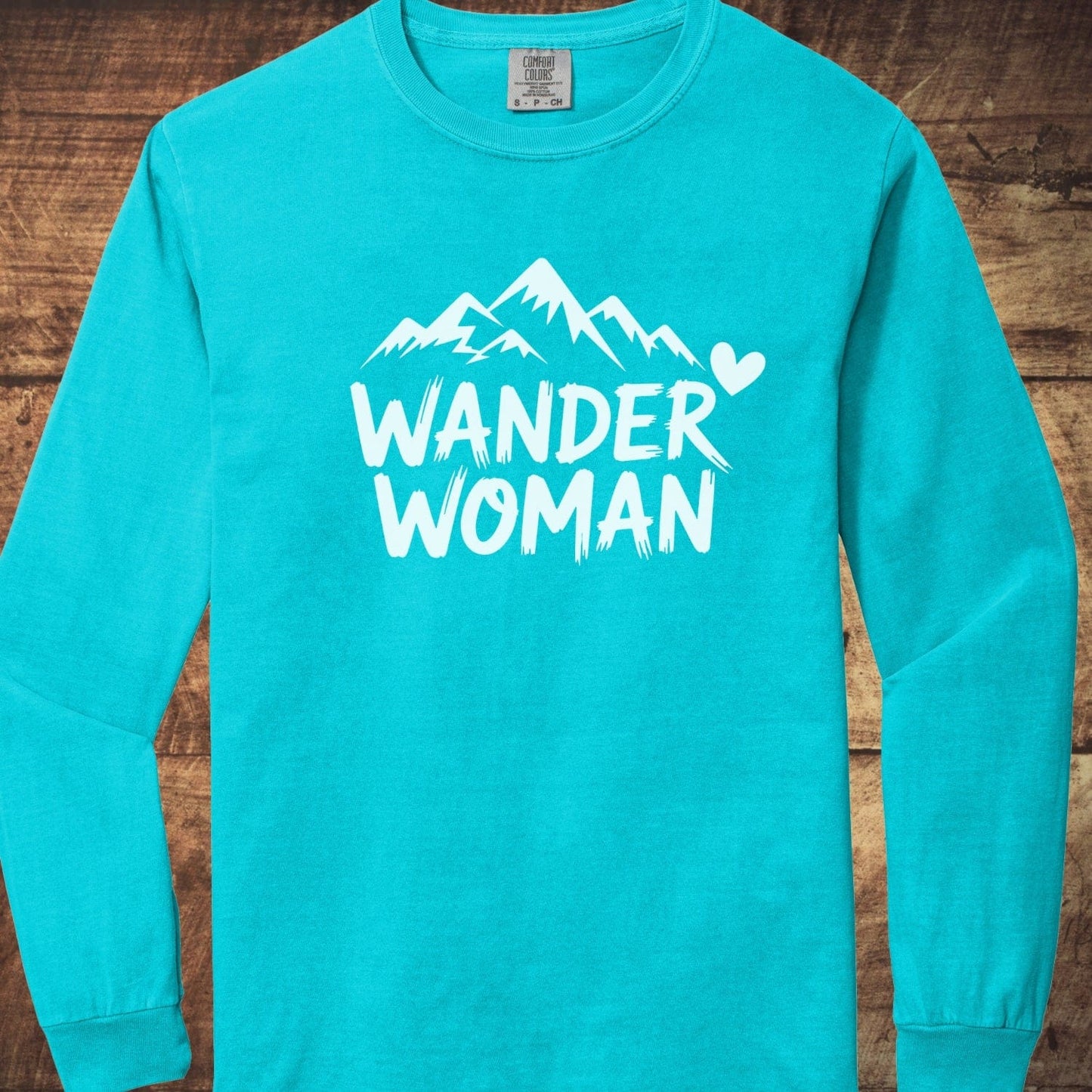 Wander Woman Comfort Colors Long-Sleeve Tee featuring stylized mountain peaks and heart graphic, crafted from soft 100% ring-spun cotton for a relaxed, classic fit.